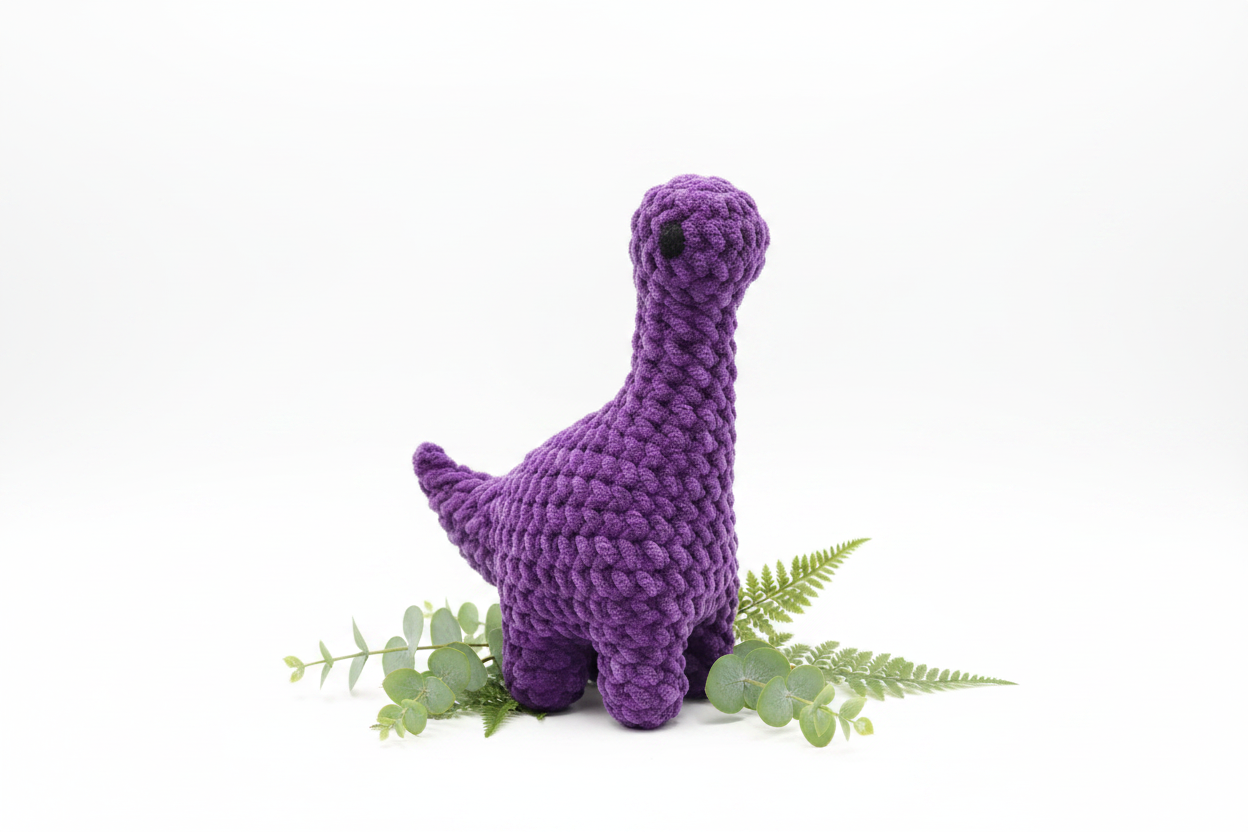 Purple crochet plush Brontosaurus on white background with greenery