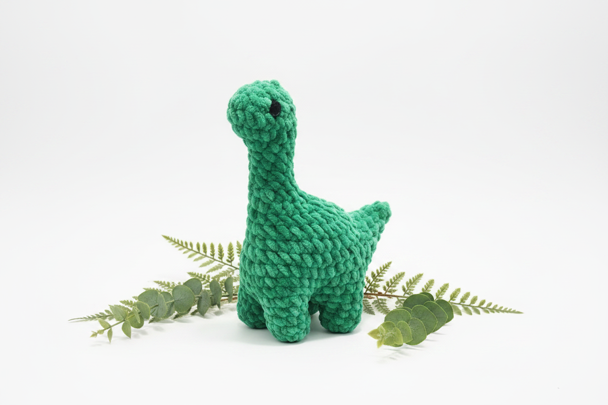 Green crochet plush Brontosaurus on white background with greenery