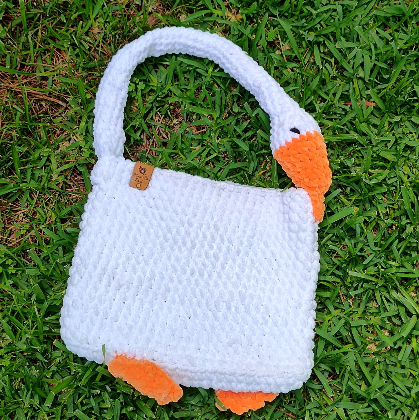 Crocheted bag designed like a goose on grass